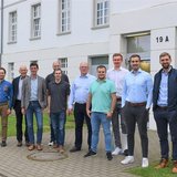 Nebeneinander stehende Personen vor einem Gebäude