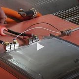 Bild aus einem Video, das Hände um eine Batterie zeigt