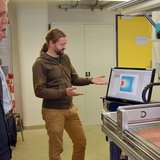 Person, die anderen Personen ein Gerät erklärt