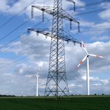 Freileitungsmast mit zwei Windrädern im Hintergrund