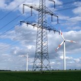Freileitungsmast mit zwei Windrädern im Hintergrund